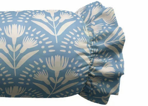 Blue and white floral patterned bolster pillow with decorative ruffled ends on a white background. Fearrington Village.