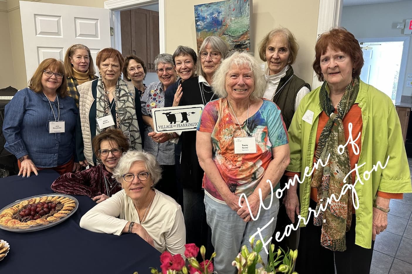 A group of women gather indoors for a Fearrington event, smiling together around a table with refreshments, with a “Women of Fearrington” overlay on the image.
