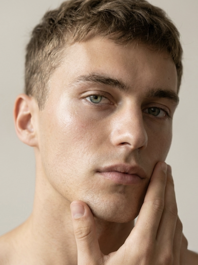 Man touching his face as part of a skincare routine. Fearrington Village.