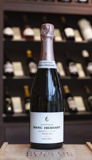 Bottle of Marc Hébrart rosé champagne on a table in front of wine bottles. Fearrington Village.