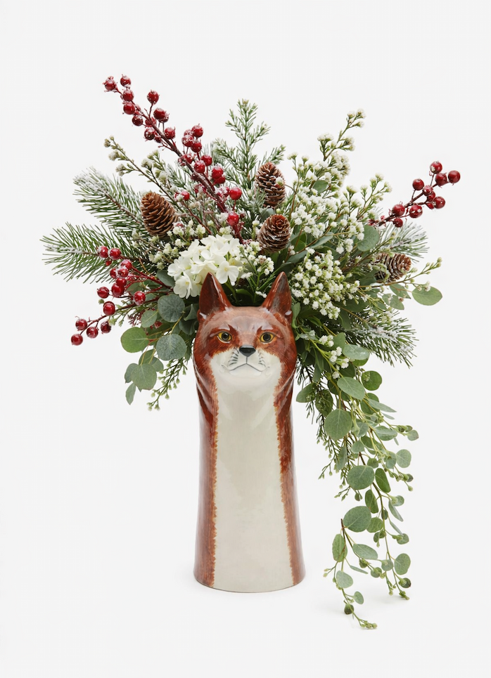 a fox head vase filled with a wintertime arrangement of florals and greenery