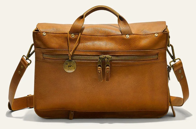 Tan leather messenger bag with top handles, shoulder strap, and exterior zippered pocket. Fearrington Village.