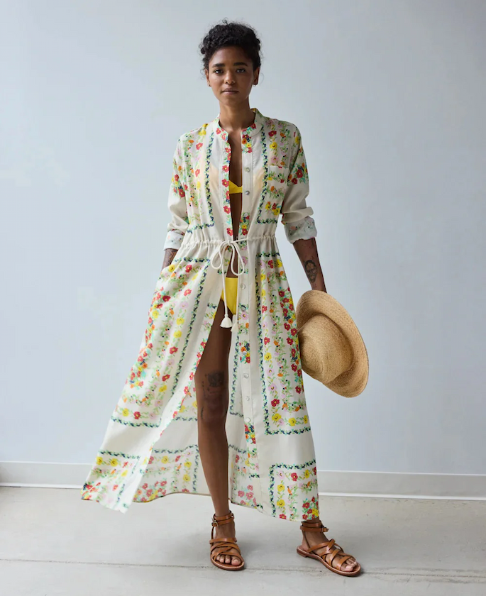 Woman wearing a floral print maxi shirtdress over a yellow swimsuit, holding a straw hat. Fearrington Village.