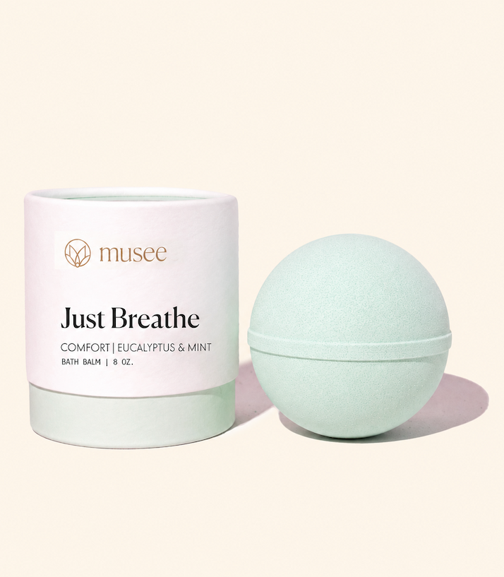 A Musee “Just Breathe” eucalyptus and mint bath balm in pale green, displayed beside its coordinating cylindrical packaging. Fearrington Village.