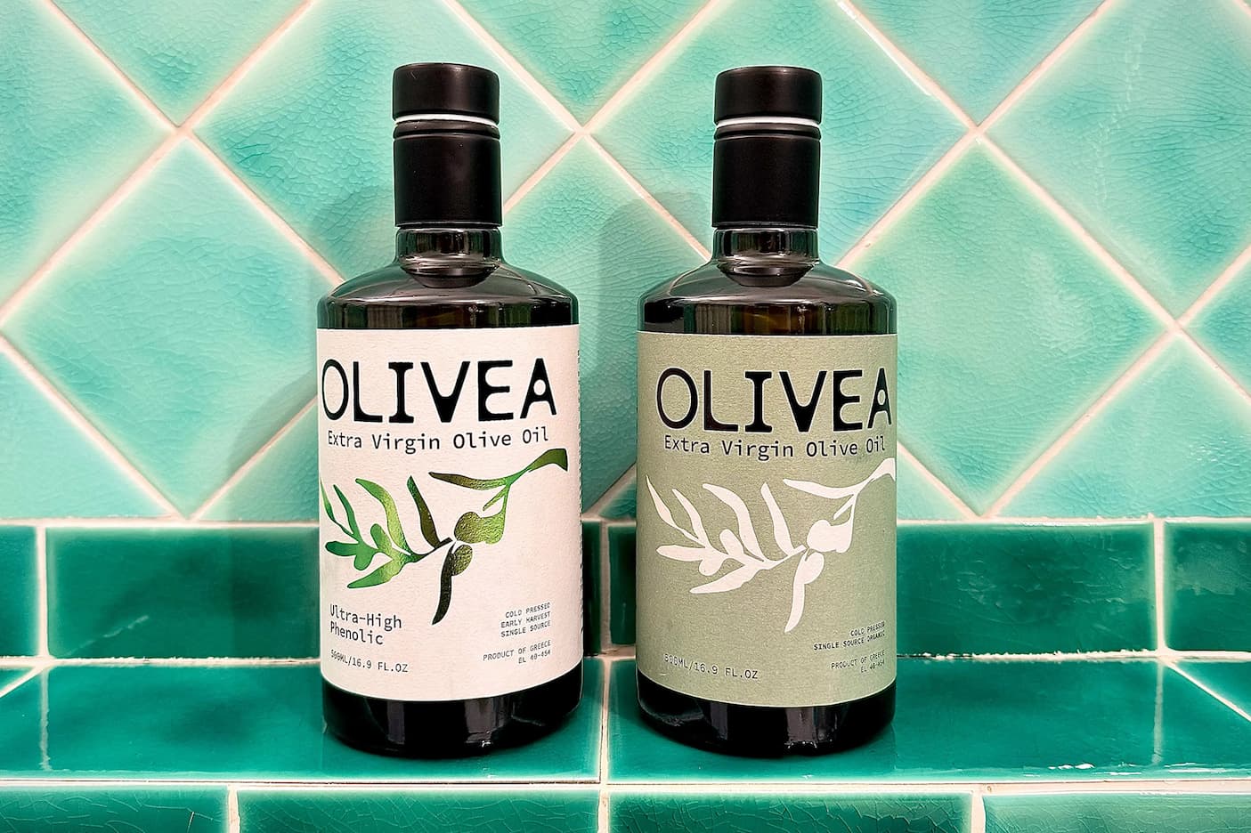 Two bottles of Olivea extra virgin olive oil displayed against a turquoise tiled backdrop. Fearrington Village.