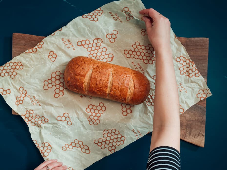 Fresh loaf of bread being unwrapped on honeycomb-patterned beeswax wrap. Fearrington Village.