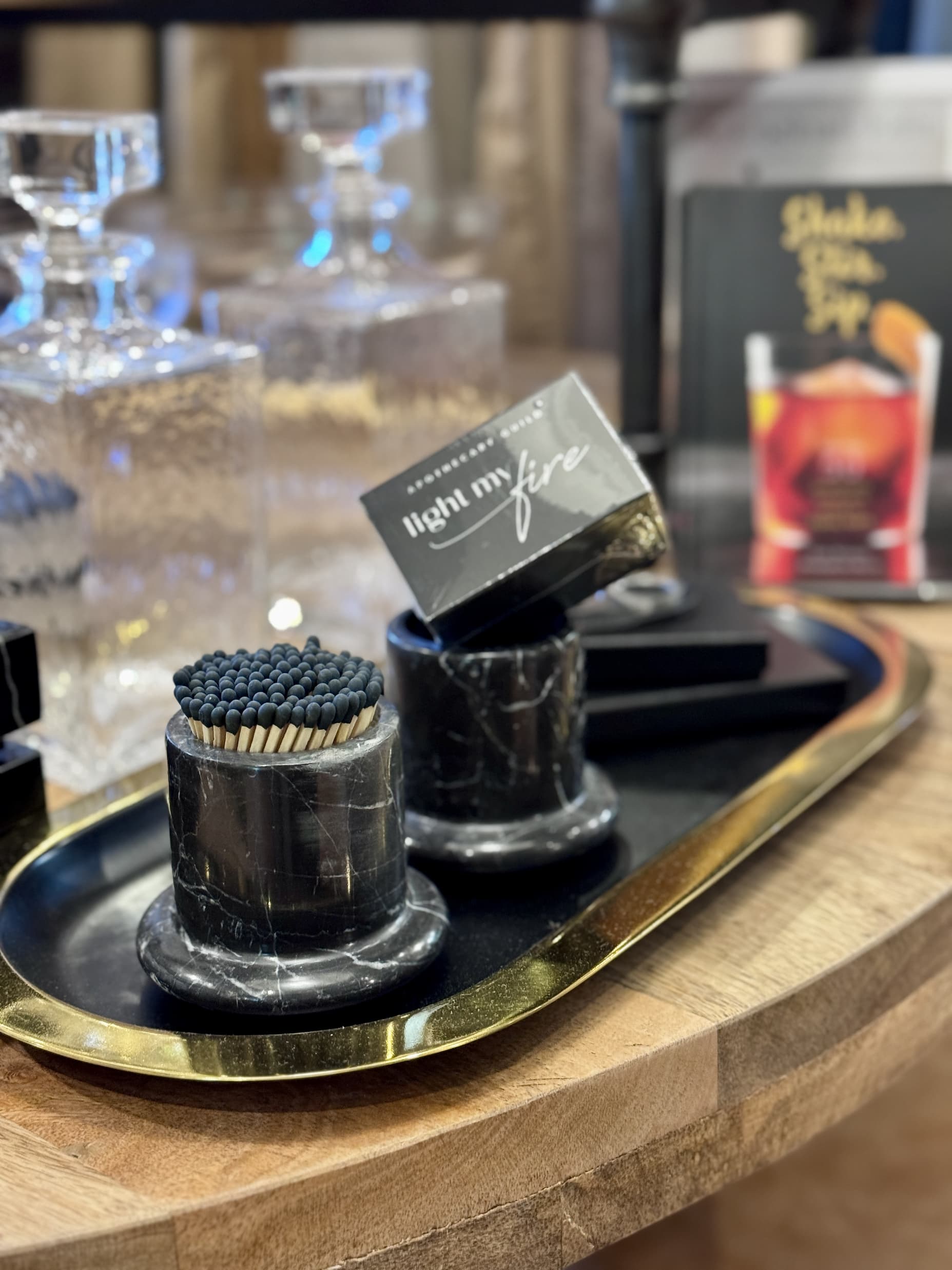 Decorative tray with marble match holders, boxed matches, crystal decanters, and cocktail accessories displayed in a home and gift shop. Fearrington Village.