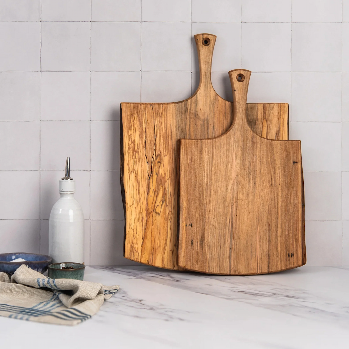 Handcrafted wooden serving boards with handles displayed against white tile. Fearrington Village.