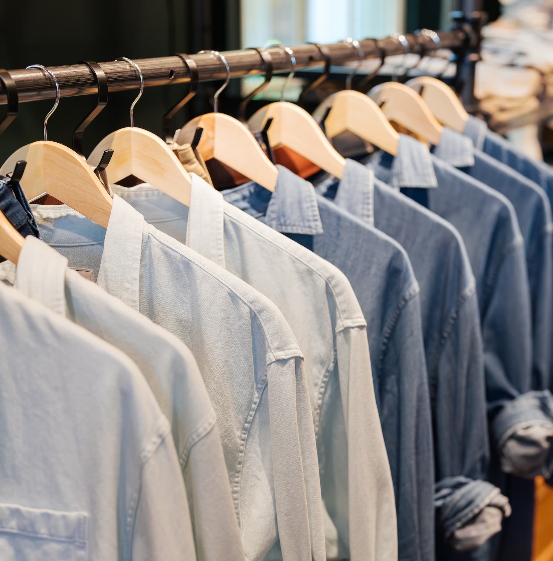 Light blue and navy men’s button-down shirts displayed on wooden hangers at Thistle & Oak in Fearrington Village.