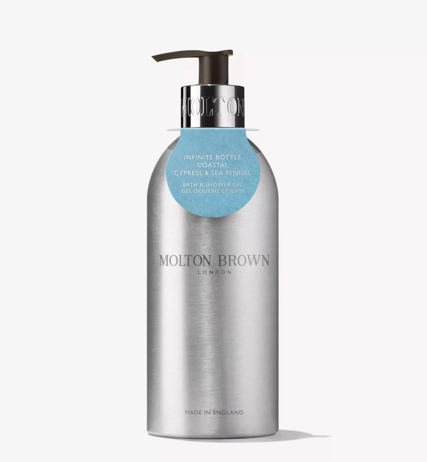 A brushed silver Molton Brown London pump bottle with a blue label reading “Infinite Bottle Coastal Cypress & Sea Fennel,” photographed on a white background.