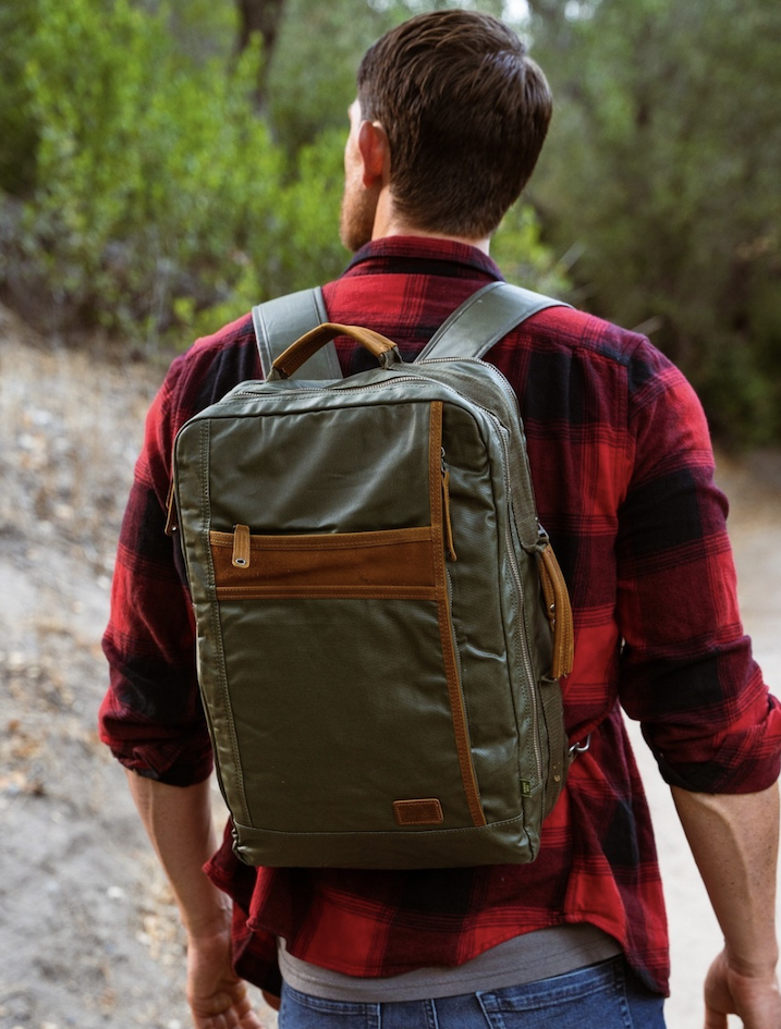 Person wearing an olive green backpack on a wooded trail. Fearrington Village.