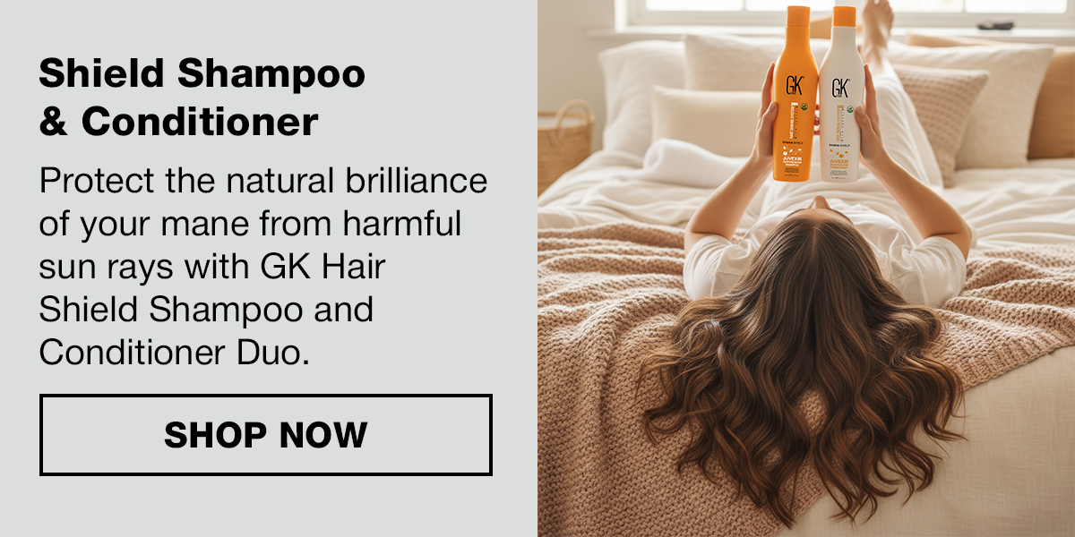 Woman lying on a bed holding GK Hair Shield Shampoo and Conditioner above her, with a Shop Now button.
