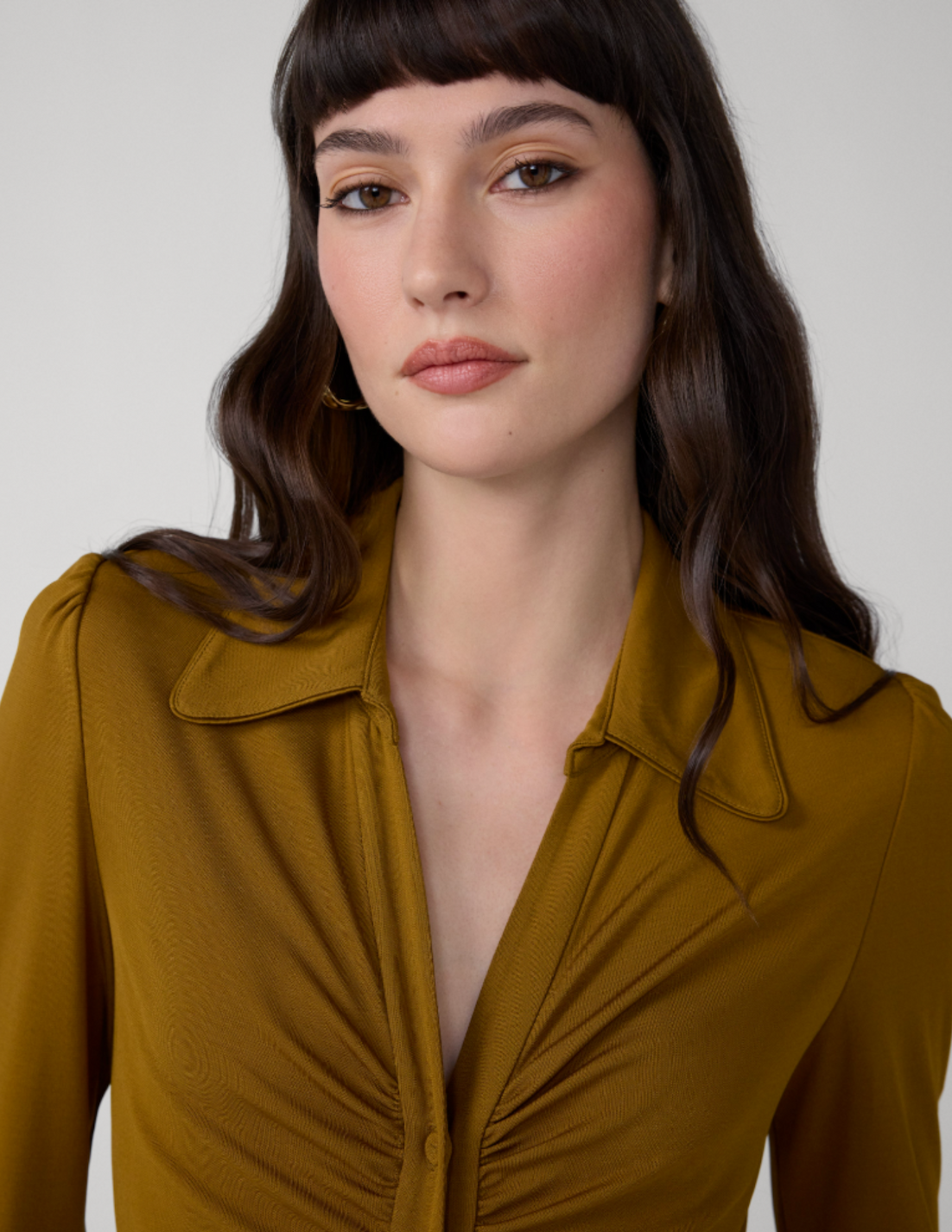 Model wearing an olive green ruched shirt dress with a pointed collar, three-quarter sleeves, and a button-front silhouette.