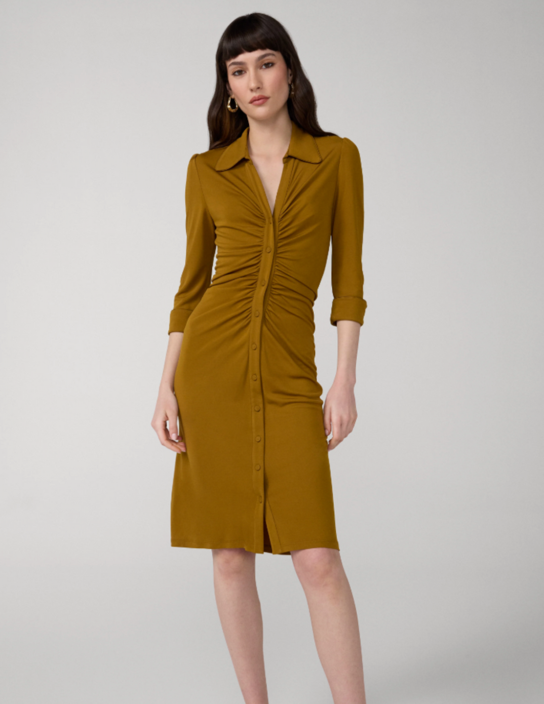 Model wearing an olive green ruched shirt dress with a pointed collar, three-quarter sleeves, and a button-front silhouette.