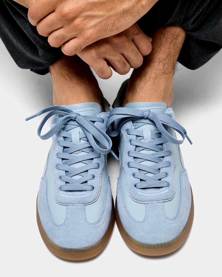 an image of a person wearing blue sneakers and a tan skirt