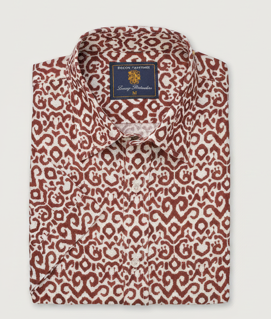 A folded short-sleeve men's shirt with a brown and white abstract pattern and a blue label.