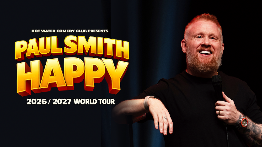 Promotional poster for a stand-up comedy tour featuring a performer holding a microphone on stage under dark lighting. Large bold yellow and orange text reads “PAUL SMITH – HAPPY,” with smaller text above saying “Hot Water Comedy Club presents” and below reading “2026 / 2027 World Tour.” The performer wears a black shirt, a wristwatch, and visible arm tattoos, leaning casually with one hand on a stool.