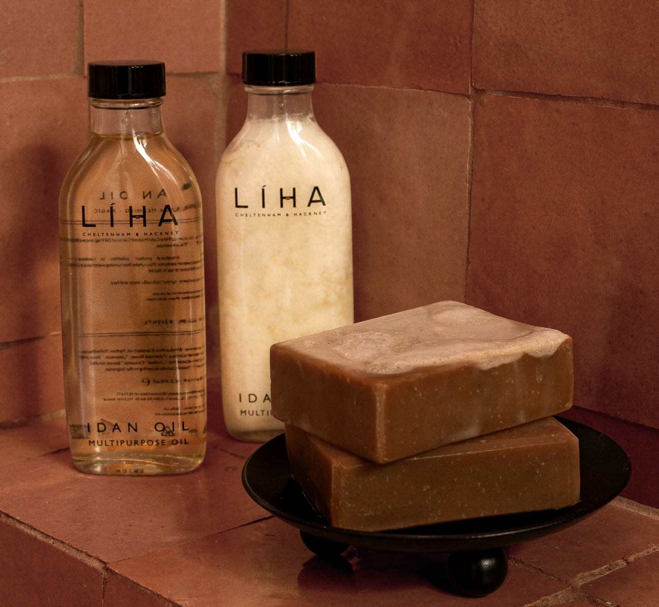 Two glass bottles, one containing melted oil and the other solid beside foam covered soap.