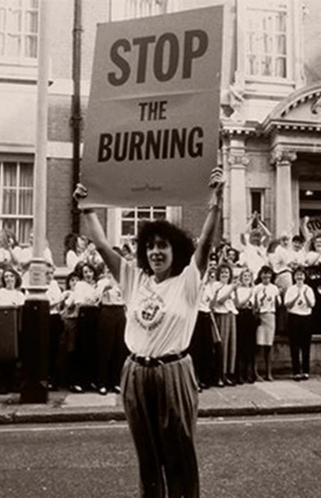 Anita Roddick holding placard that reads "Stop the burning"