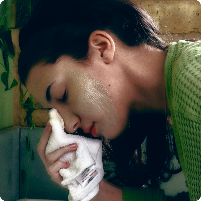 Woman washes her face with a damp cloth