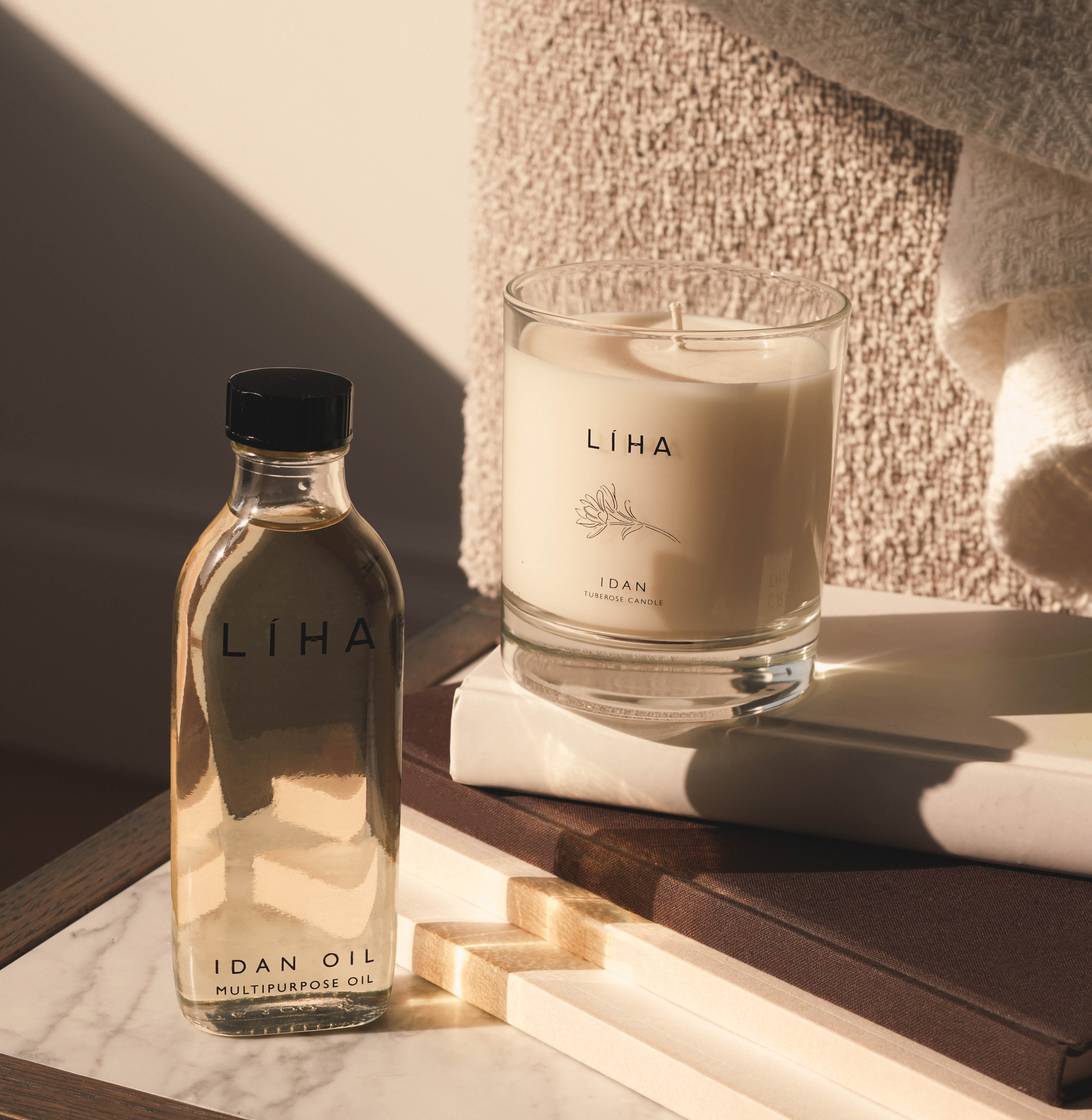 A bottle of Idan Oil beside an unlit candle with the same scent