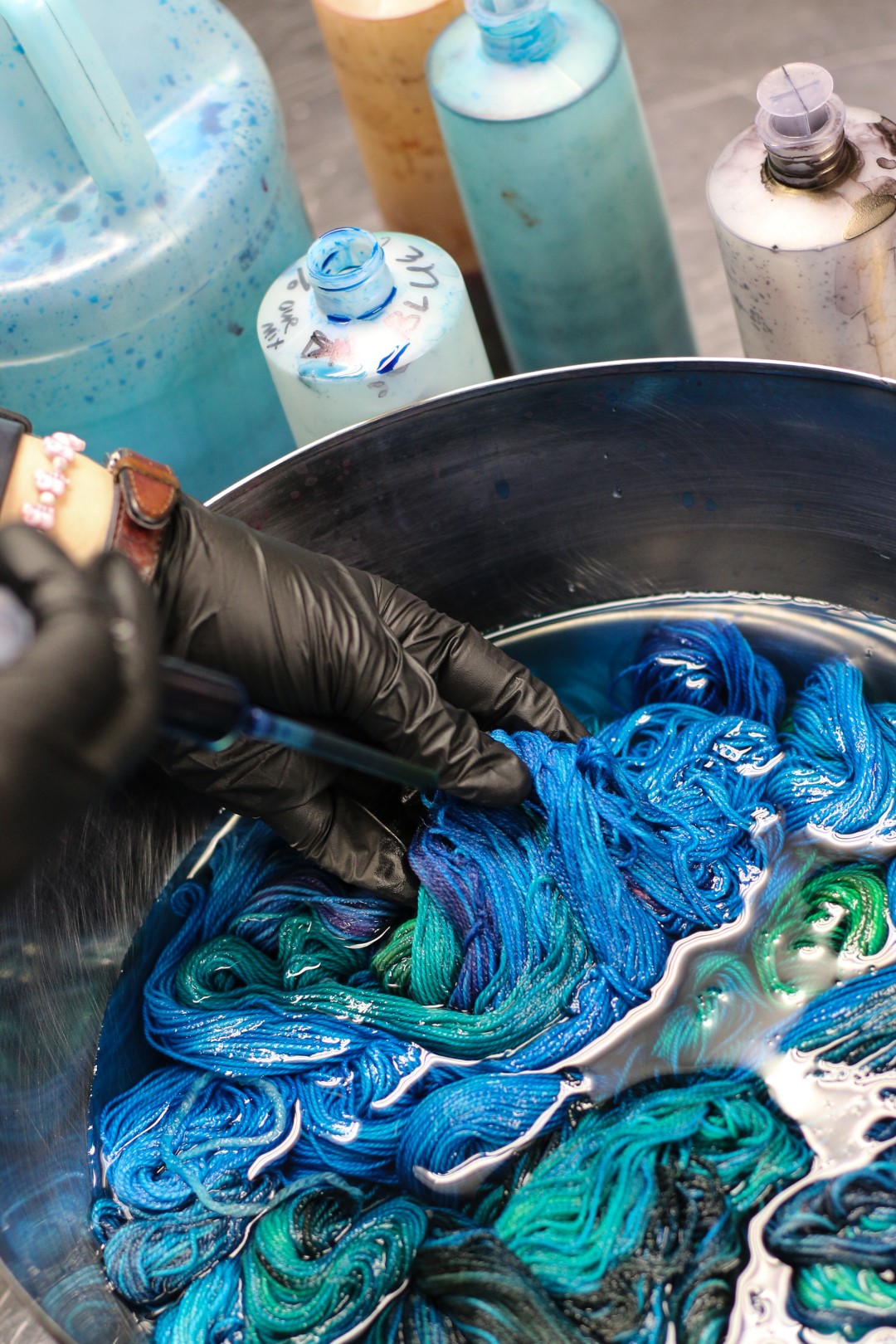 a pair of gloved hands half submerged into a steel dyepot,full of blue dye, dyeing mini-skeins for the SpaceCadet's Mini-Skein Club