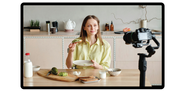 Food influencer in a kitchen filming, holding avocado toast