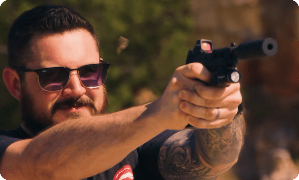 Person firing handgun with optic.