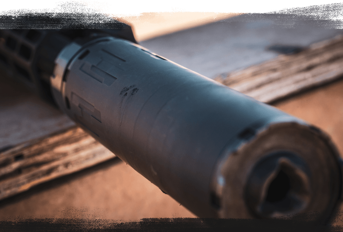 Close-up of matte black suppressor with engraved patterns.