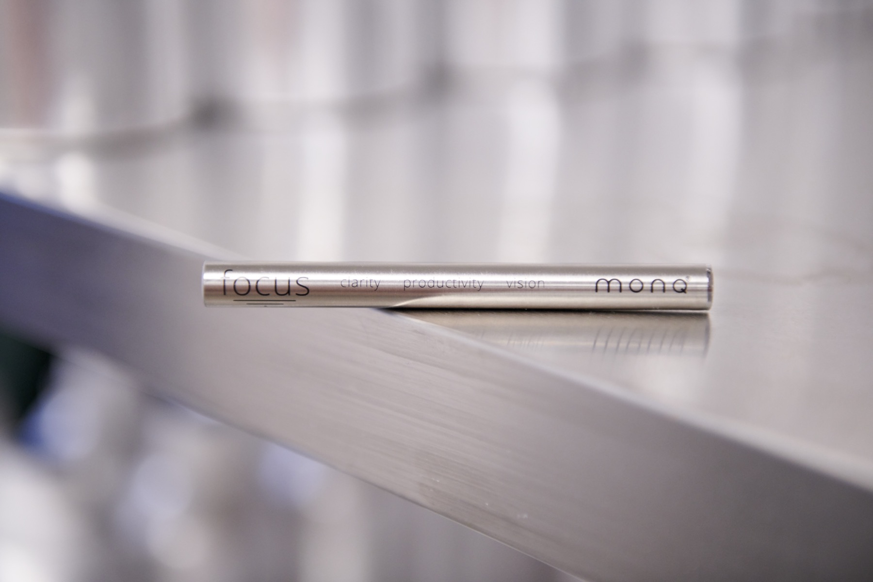 MONQ focus diffuser on a minimal brushed-metal surface — portable botanical aromatherapy for sustained afternoon clarity