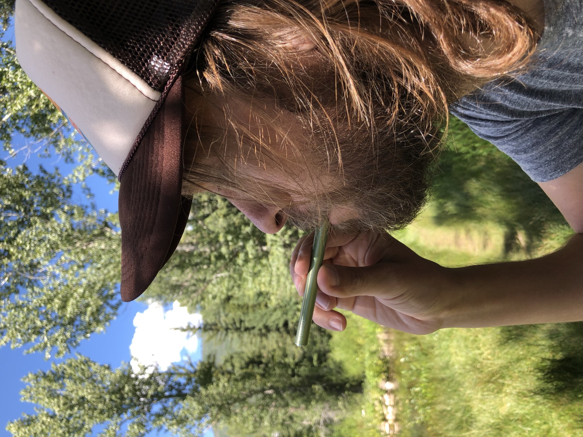 Man inhaling MONQ diffuser on a sunlit forest trail — the same bioactive terpenes found in forest air, concentrated in a single portable breath