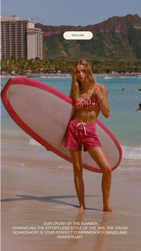 woman wearing a pink boardshort on beach holding alongboard