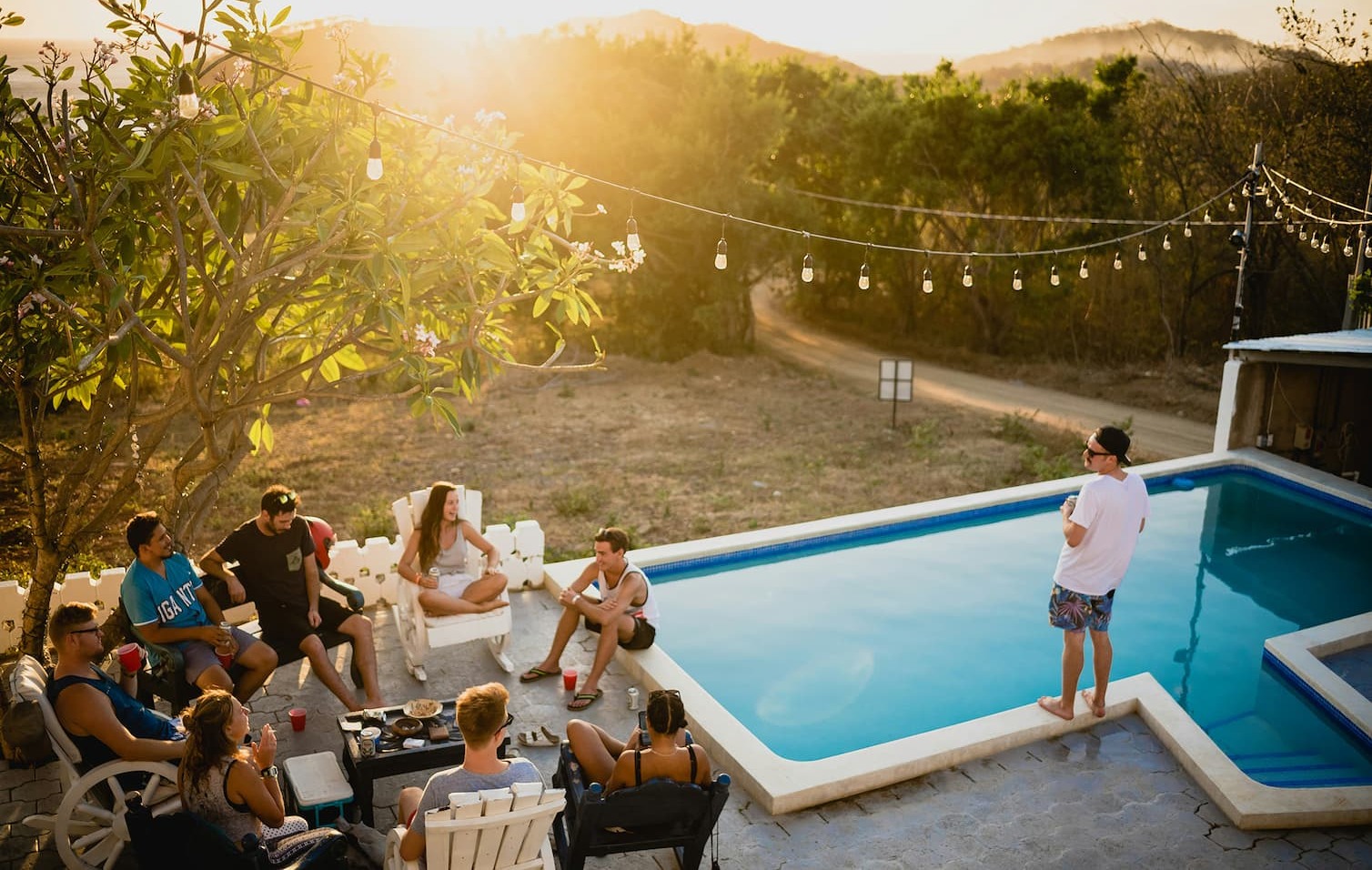 a group of people hanging in a backyard at sunset