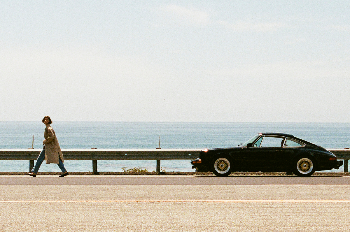 Editorial Image | Model in   On coastal road with a vintage Porsche