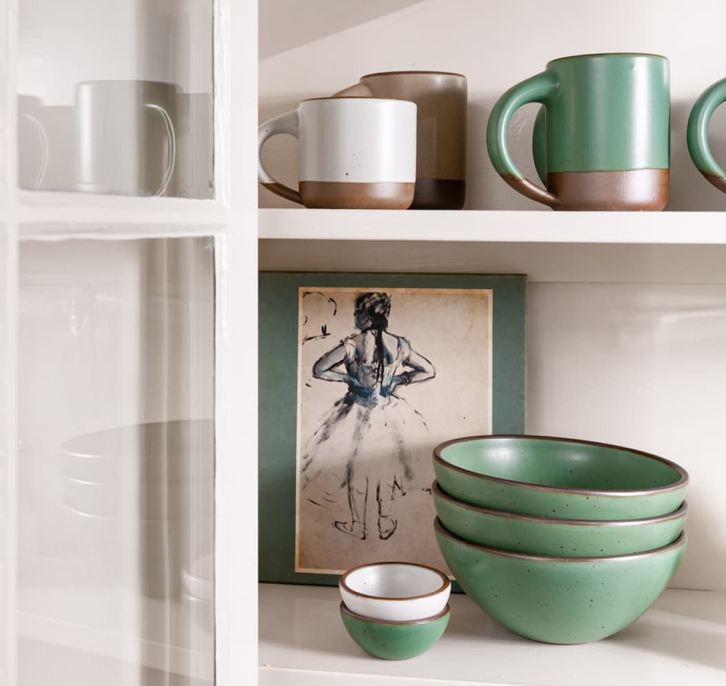 A sunlit cabinet holds pottery in Lagoon, Morel and Eggshell. A print of one of Degas' dancers is in the back.