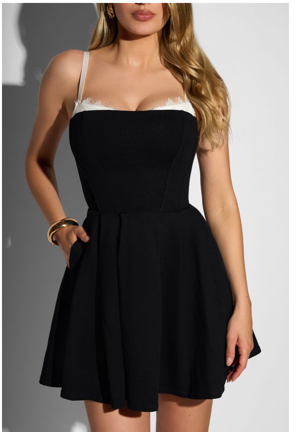 Black dress with a fitted bodice and flared skirt, featuring white lace straps and pockets.