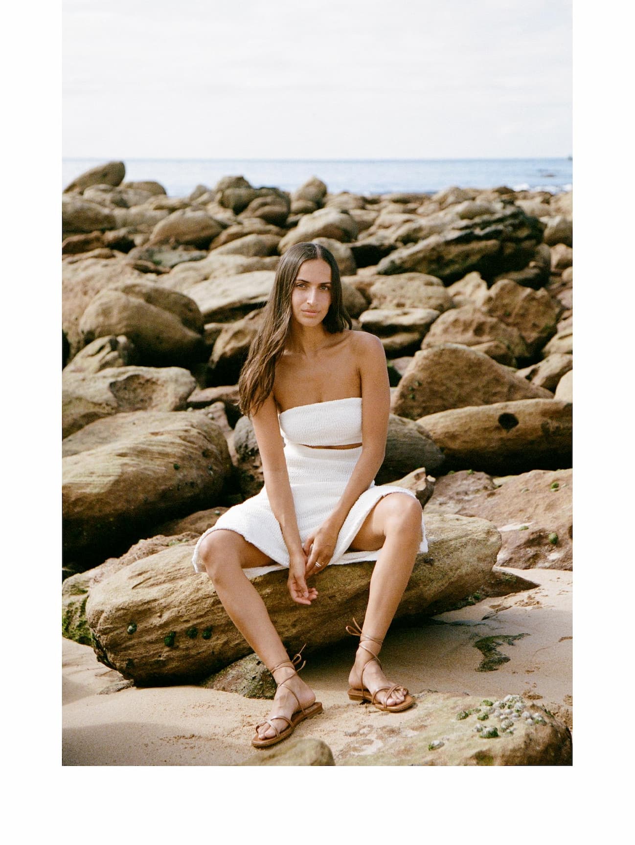 an image of a woman sitting on a log on the beach