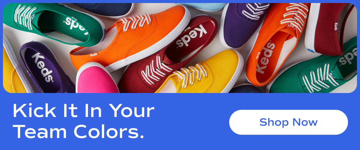 A vibrant flat lay of Keds Champion Canvas lace-up sneakers in an array of bold colors, including red, yellow, green, blue, purple, and orange. The shoes are arranged in an overlapping pattern, creating a lively and energetic composition. Text overlay reads "Kick It In Your Team Colors". A white button with blue text says "Shop Now".