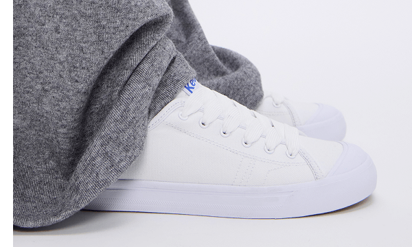 Floor-pooling grey pants paired with the Cruise Canvas Slip-On in white.
