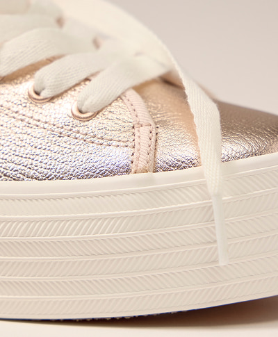 A closeup of the thick sole and shiny metallic leather on the Triple Up Metallic Leather Platform Lace-Up in rose gold.