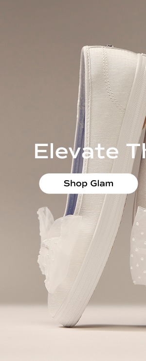 A pair of the new Maisie Grosgrain Ballet Slip-Ons with Tulle Bow embellishment at the toe in snow white shown balancing on toe and showcasing the blue blissARCH comfort insoles.