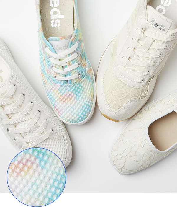 Overhead shot of four Keds shoes arranged on a white surface. From left to right: the Keds Triple Kick Cotton Mesh lace-up in egret, featuring a textured mesh upper and white laces; the Keds Champion Cotton Mesh lace-up shoe in multi-color, displaying a pastel tie-dye pattern on its mesh upper and white laces; the Keds Rena Floral Lace lace-up sneaker in egret/cream, with a floral lace overlay and white laces; and the Keds Square Toe Mary Jane shoe in cream, featuring a subtle patterned textile. A circular inset in the lower left provides a detailed close-up of the pastel tie-dye mesh texture.
