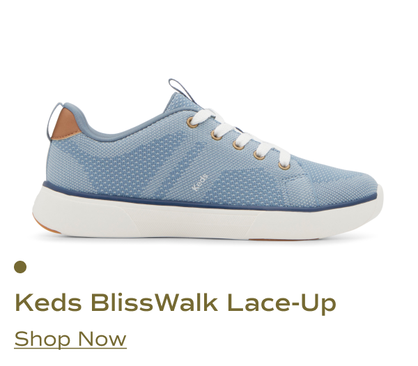A side view of the Keds BlissWalk knit lace-up shoe in blue, featuring a breathable knit upper, white laces, gold eyelets, and a cushioned white outsole with navy trim. A cognac brown heel accent adds contrast. Shop Now.