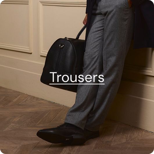 Man in grey formal trousers lent against wall