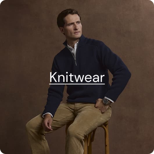 man in navy quarter zip sat on a stool