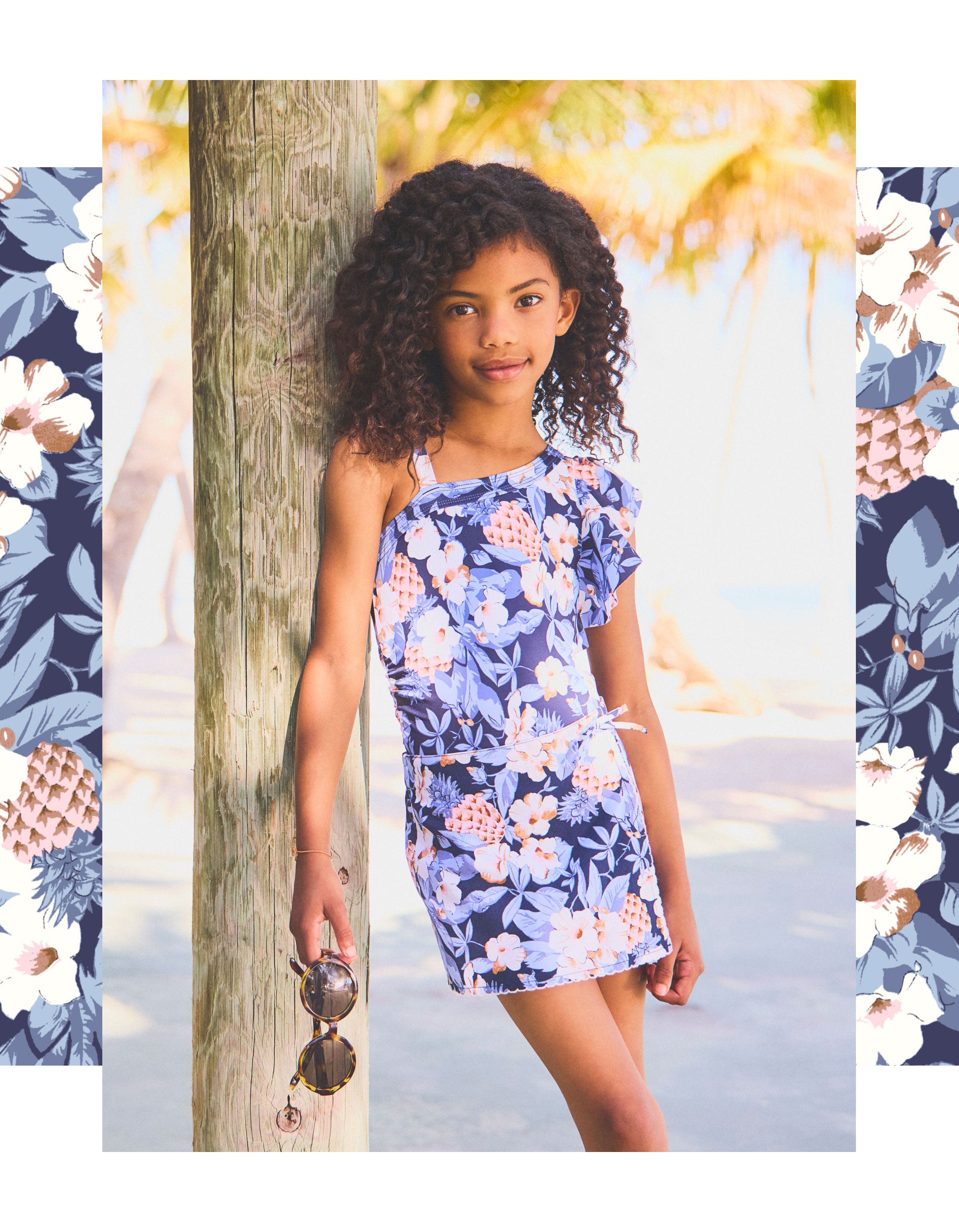 Young girl in floral dress posing by wooden post