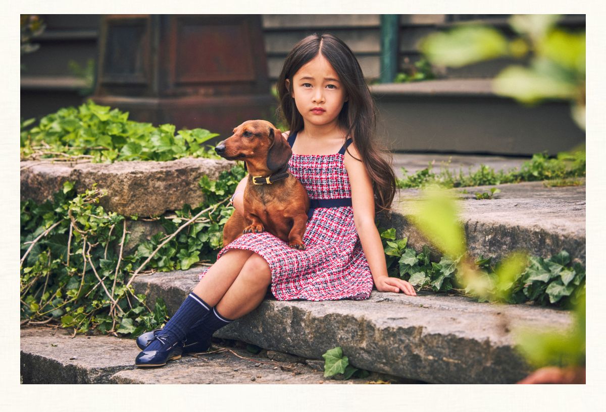 Young girl in plaid dress with dog