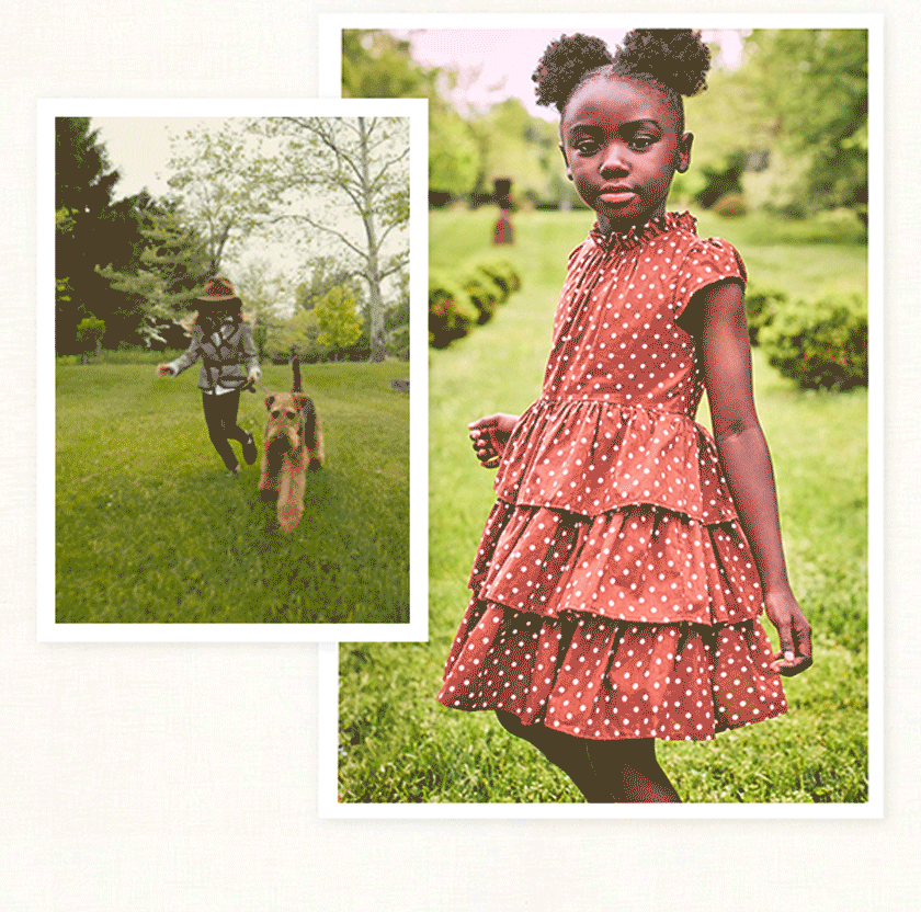 Two children playing outdoors in a green park setting, one running with a dog, the other posing in a red polka dot tiered dress with puff buns hairstyle
