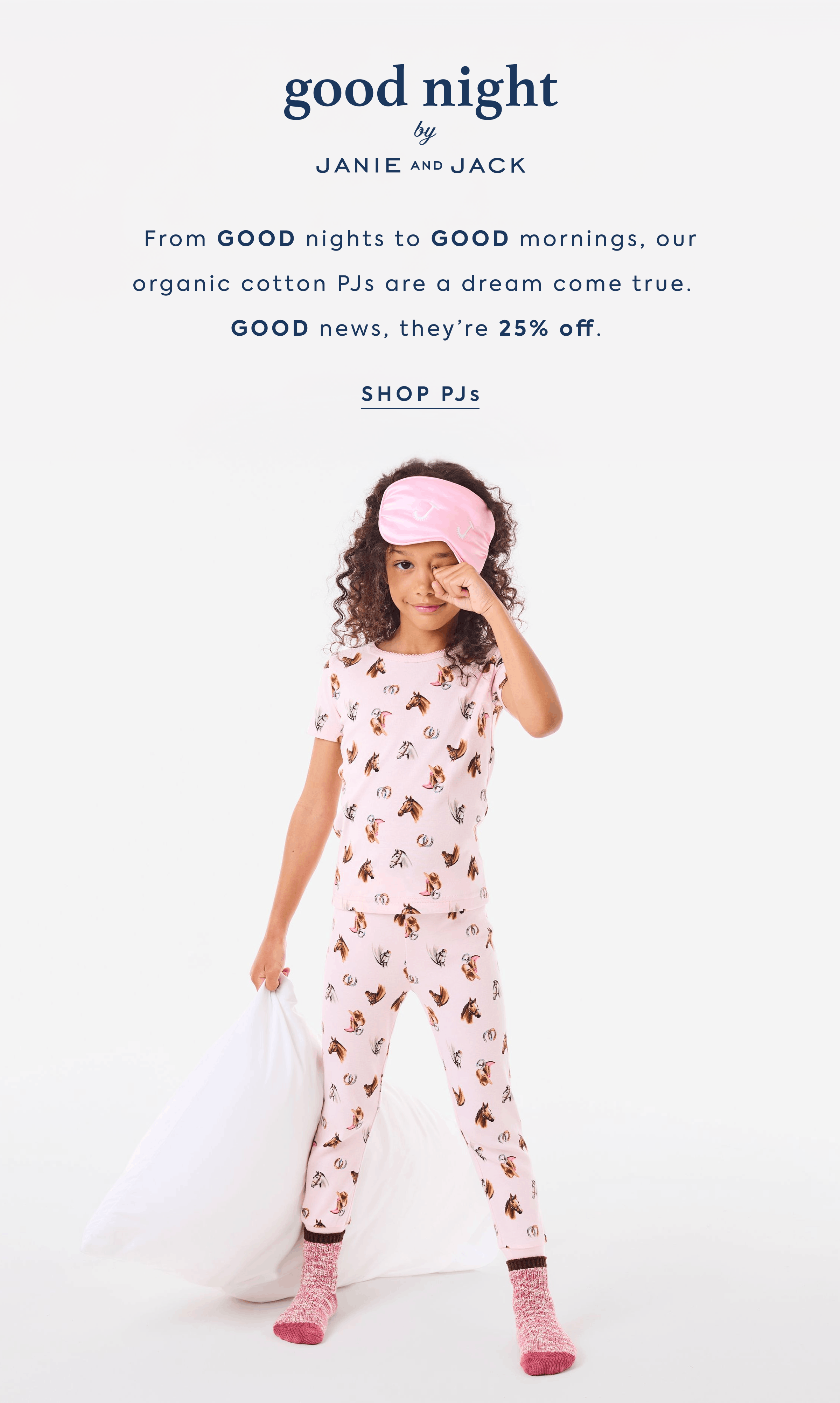 Girl in pink horse-print pajamas with sleep mask holding a pillow