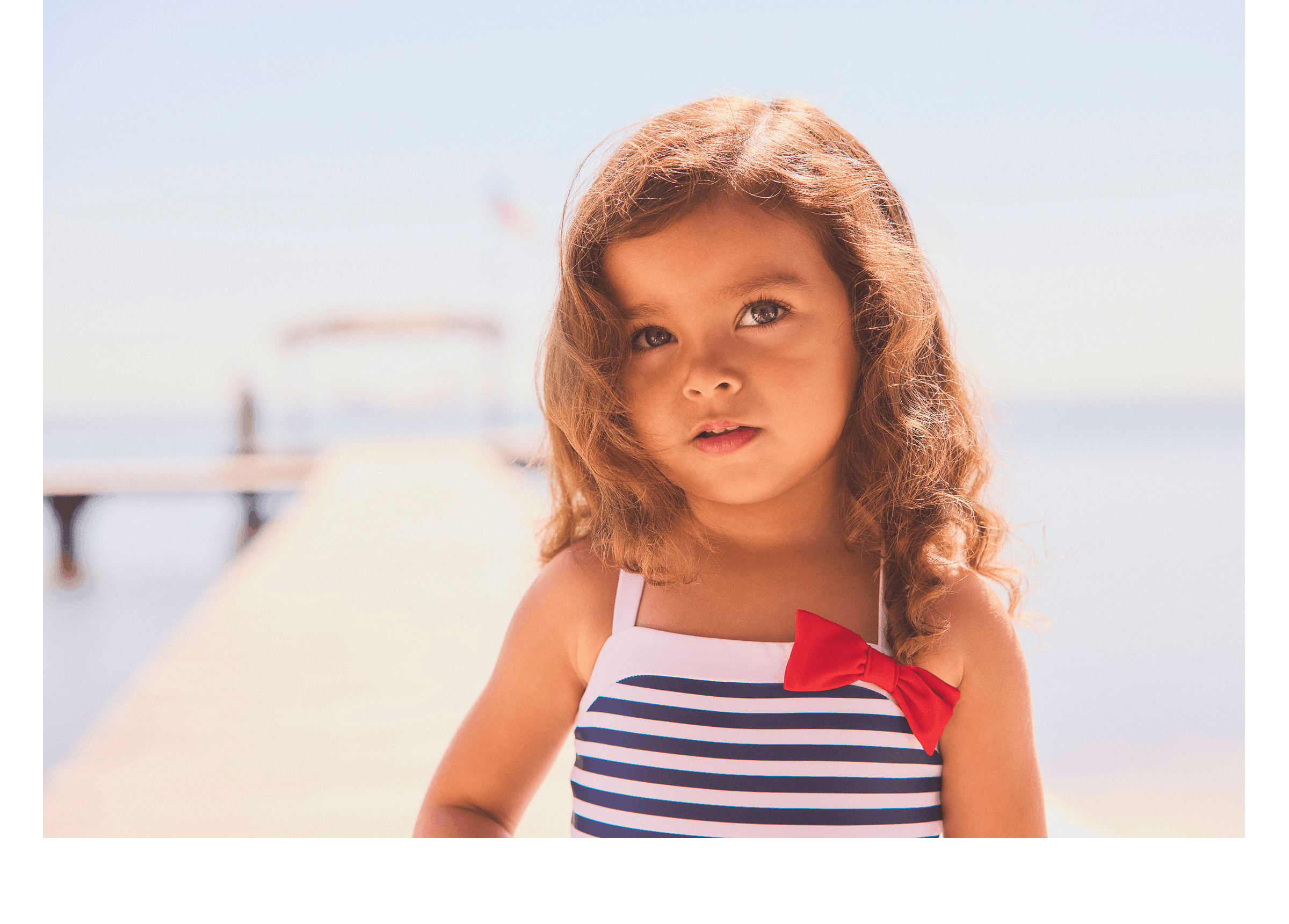 Two children wearing American flag apparel standing by water with wooden dock in background